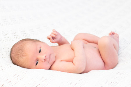 newborn baby lies in the bed and smilesの写真素材