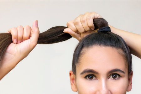 Beautiful girl model with shiny brown straight long hair. Hair care products. Keeps hair in a fist,...