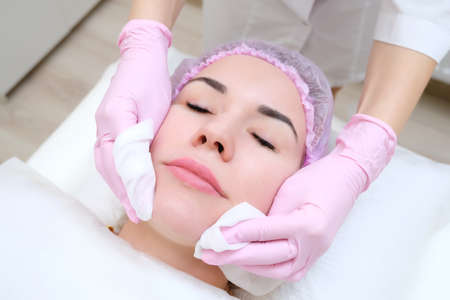 cosmetology. Close up picture of lovely young woman with closed eyes receiving facial cleansing...