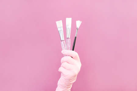 Cosmetology concept, beautician in hand are brushes, pink backgroundの写真素材