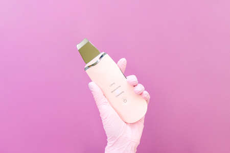 Cosmetology concept, cosmetologist in hand are ultrasonic, pink background. ultrasonic face cleanerの写真素材