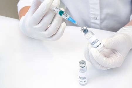 COVID-19 vaccine in researcher hands, female doctor holds syringe and bottle with vaccine for...