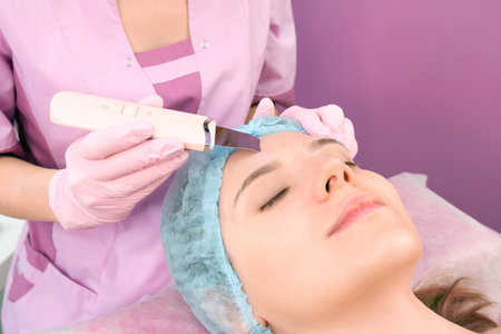 ultrasonic cleaning of the face of a young woman in a cosmetology office.