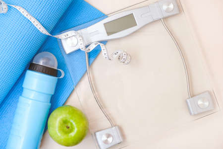 fitness and sports concept. yoga mat, scales, green appleの写真素材