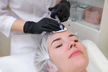 Cosmetic injections for skin rejuvenation. Cosmetologist injects a syringe into the skin of a young woman.の写真素材