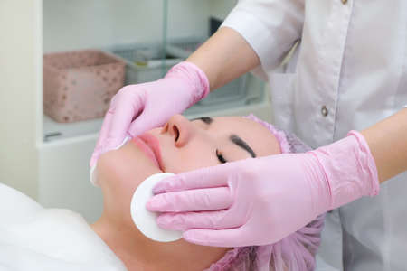 cosmetology. Close up picture of lovely young woman with closed eyes receiving facial cleansing...