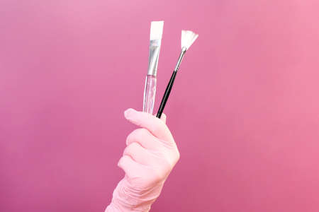 Cosmetology concept, beautician in hand are brushes, pink backgroundの写真素材