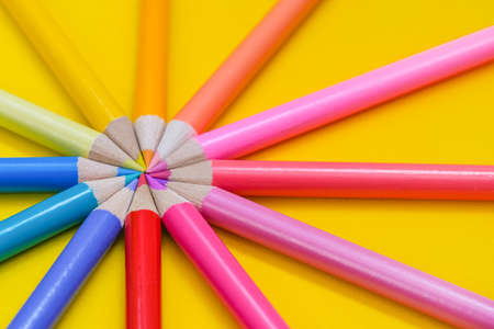 Many different colored pencils on a yellow background. Colored pencils are arranged in a circle.の写真素材