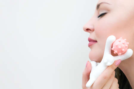Roller massage of the face of a young beautiful woman. Portrait of a young woman close up. copy spaceの写真素材