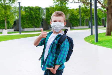Schoolboy in a protective mask on the street on the way to school. Back to school. Shows like