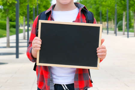 Schoolboy with a sign in his hands on the street on the way to school. Back to schoolの写真素材