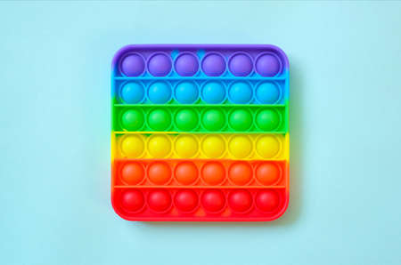 Rainbow pop it toy fidget on a background of empty copy space. blue background