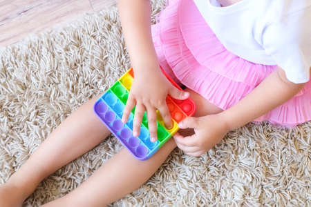 Kids play with pop it sensory toy. Stress and anxiety relief. Trendy silicon fidgeting game for stressed children and adults. Squishy soft bubble toys.の写真素材