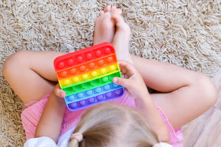 Girl play with pop it sensory toy. Stress and anxiety relief. Trendy silicon fidgeting game for stressed childrenの写真素材