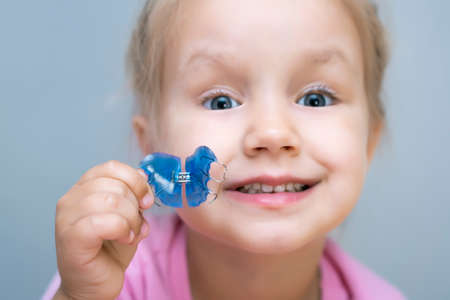 Dental plate. Expansion of the jaw in a child. A plate to heaven. There is not enough room for the molars. Happy girl holding an orthodontic plate in her handsの写真素材