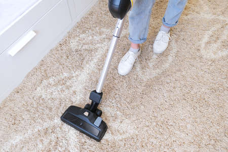 cordless vacuum cleaner is used to clean the carpet in the room. Housework with a new handheld vacuum cleaner. House cleaning, care and technology concept.の写真素材