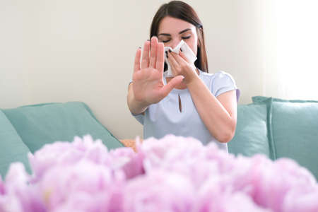 young woman sneezes from flower allergy. Pollen allergy