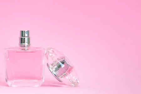 elegant perfume bottle with open lid on pink pastel background