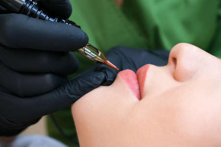 Macro photo of the process of applying permanent makeup of a natural color on a womans lips.の写真素材
