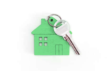 Figure of a mini house of green color with keys on an isolated white background.の写真素材