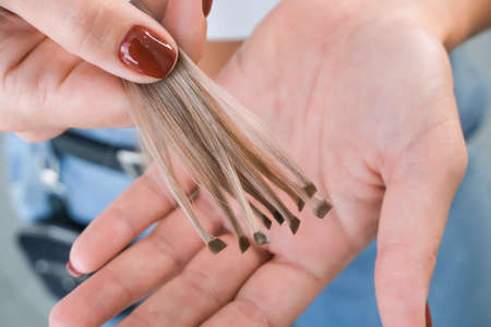 Hair extension. Hair strands with capsules in hand. Preparing for hair extensions in a beauty salonの写真素材