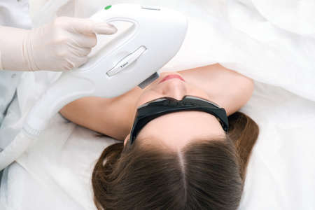 Laser hair removal of the mustache and chin of a young beautiful woman. Depilation on the face....