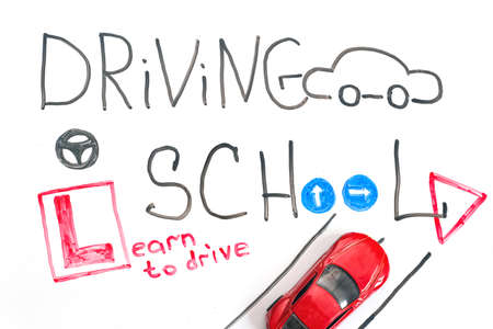 Driving school chalkboard, Educational and Creative composition with the Driving school caption. toy car model. traffic signs. White isolated background, board for markersの写真素材