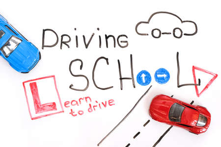 Driving school chalkboard, Educational and Creative composition with the Driving school caption. toy car model. traffic signs. White isolated background, board for markersの写真素材