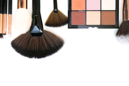 Decorative cosmetics and makeup brushes on a white isolated background, top view. place for your...