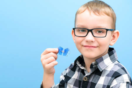 Dental orthodontic plate. Expansion of the jaw in a child. plate in the sky. Not enough room for molars. Happy boy holding an orthodontic plate in his handsの写真素材