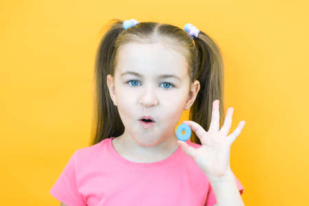 speech therapy. Toddler girl holding the letter O in her hands. Classes with a speech therapist. girl on isolated yellow backgroundの写真素材