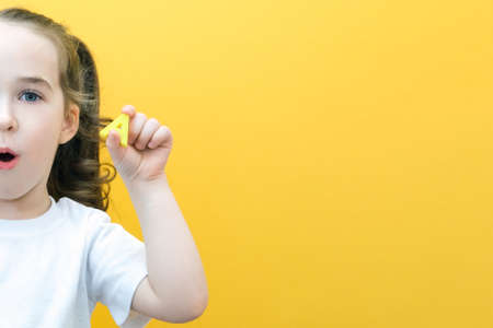 speech therapy. Toddler girl holding the letter A in her hands. Classes with a speech therapist. girl on isolated yellow backgroundの写真素材