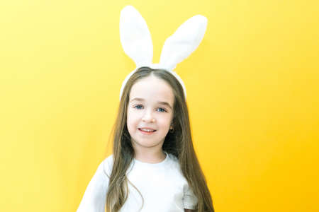 cheerful girl with rabbit ears on her head on a yellow background. Funny happy child. copy space for text, mockupの写真素材