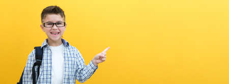 cheerful, happy child points up, copy space for text. Smiling, enthusiastic schoolboy in a plaid shirt showing off. advertising concept.の写真素材