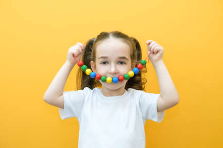speech therapy, the development of fine motor skills. Toddler girl stringing beads on a string. happy child. smile beadsの写真素材