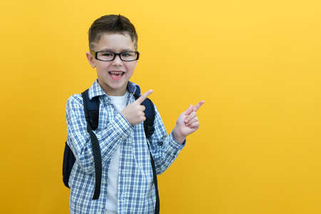 Child boy in glasses isolated on yellow paper wall. great idea. Happy smiling schoolboy goes back to school. Success, motivation, winner, genius concept.の写真素材