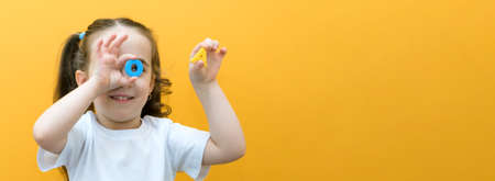 speech therapy. Toddler girl holding the letter O and A in her hands. Classes with a speech therapist. girl on isolated yellow backgroundの写真素材