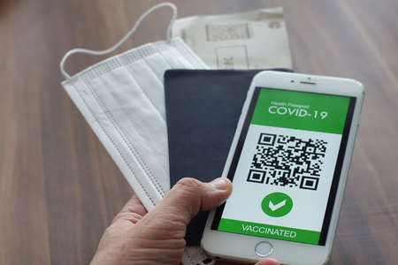 Person in airport using mobile app in phone to show vaccination certificate and covid-19 test results for travelのeditorial素材