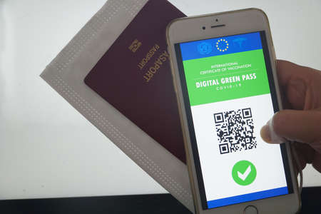 The digital green pass of the european union with the QR code on the screen of a mobile phone held...