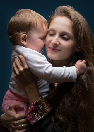 Young beautiful woman hugging her little daughterの写真素材