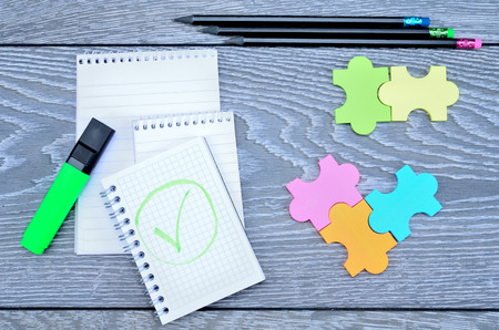 notebook on gray wooden table with paper puzzle