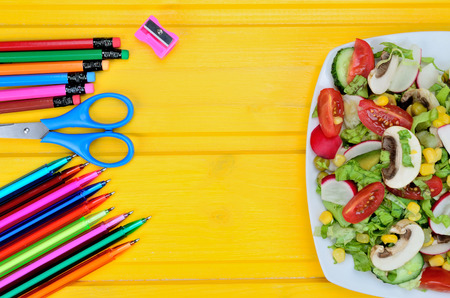 supplies and salad on yellow wooden tableの写真素材