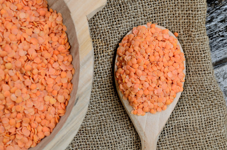 red lentil in spoon with sack on wooden tableの写真素材