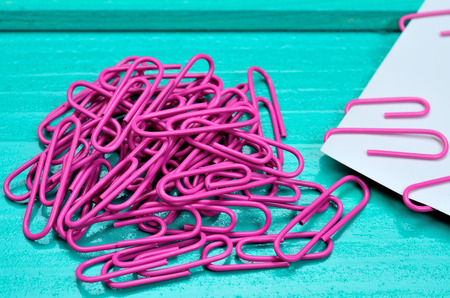 pink paperclips on green wooden tableの写真素材