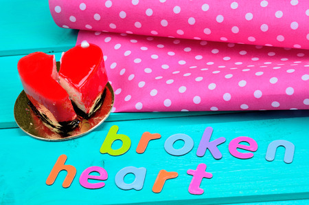 text broken heart with cake mousse on green wooden tableの写真素材
