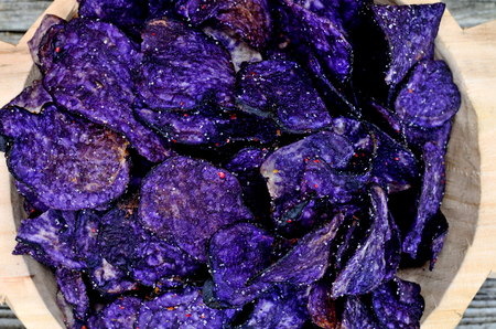 blue potato chips in bowl on wooden tableの写真素材
