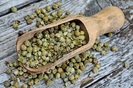 green peppercorn in scoop on wooden tableの写真素材