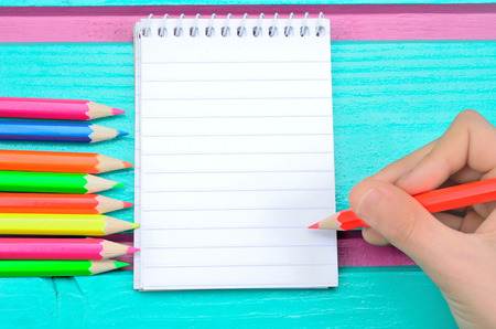 hand of child write on notebook on green wooden table