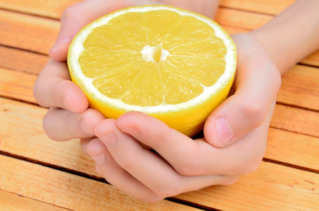 hand hold a half of lemon on wooden tableの写真素材