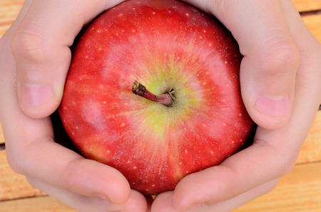 hand hold apple on wooden tableの写真素材